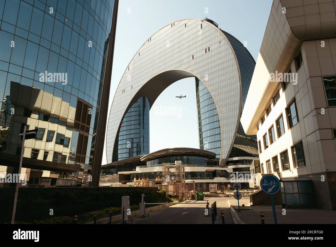 Bakou, Azerbaïdjan - 26 juin 2023 : vue rapprochée du matin de l'hôtel Crescent, avec un avion passant par la brèche au milieu de la structure Banque D'Images