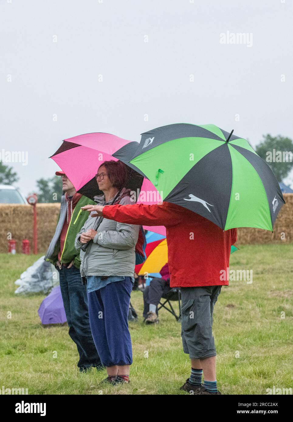 Les festivaliers du festival de musique GTSF se couvrent pendant une brève averse de pluie. Banque D'Images