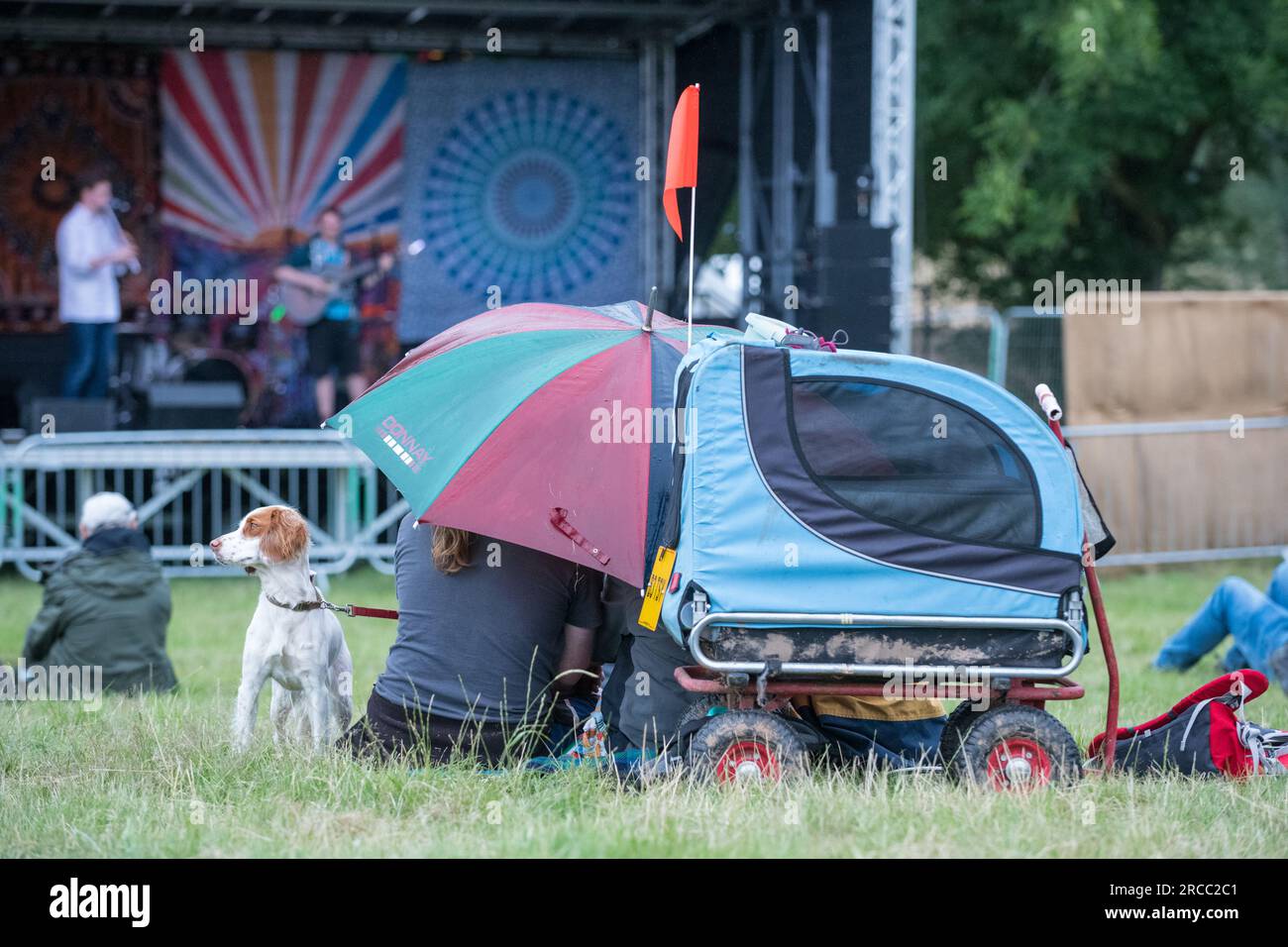 Les festivaliers avec leur chien de compagnie au festival de musique GTSF se couvrent pendant une brève averse de pluie. Banque D'Images