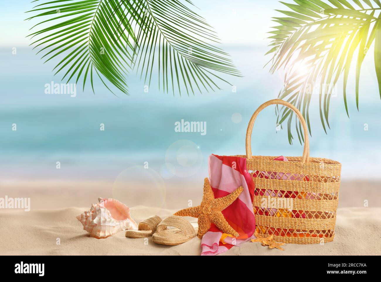 Sac avec accessoires sur la plage ensoleillée de l'océan, espace pour le texte. Vacances d'été Banque D'Images
