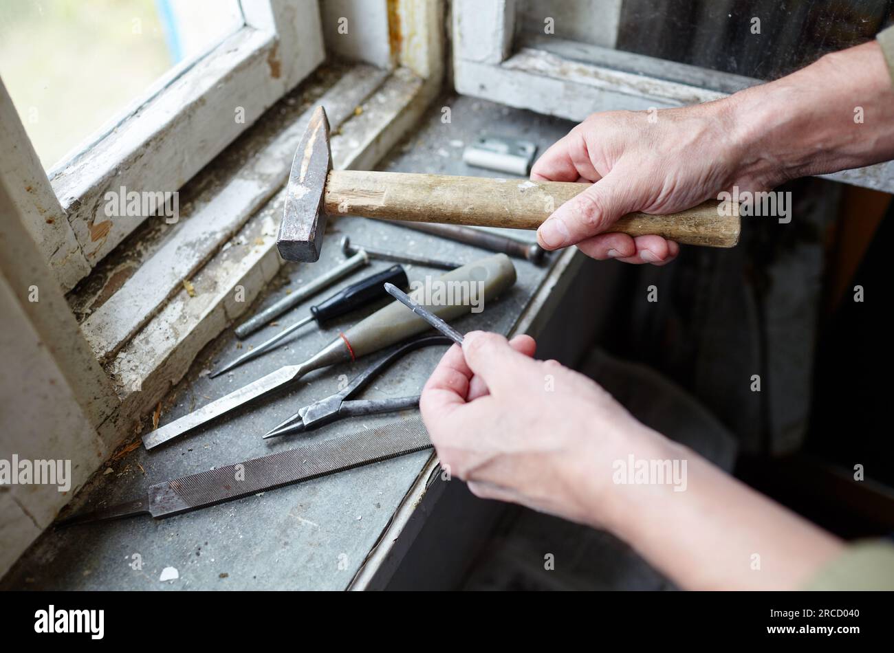 Main d'homme tenant le marteau. Réparer la vieille fenêtre endommagée ou démonter avant d'installer une nouvelle, gros plan. Réparation d'un cadre de fenêtre, en utilisant des instruments pour Banque D'Images