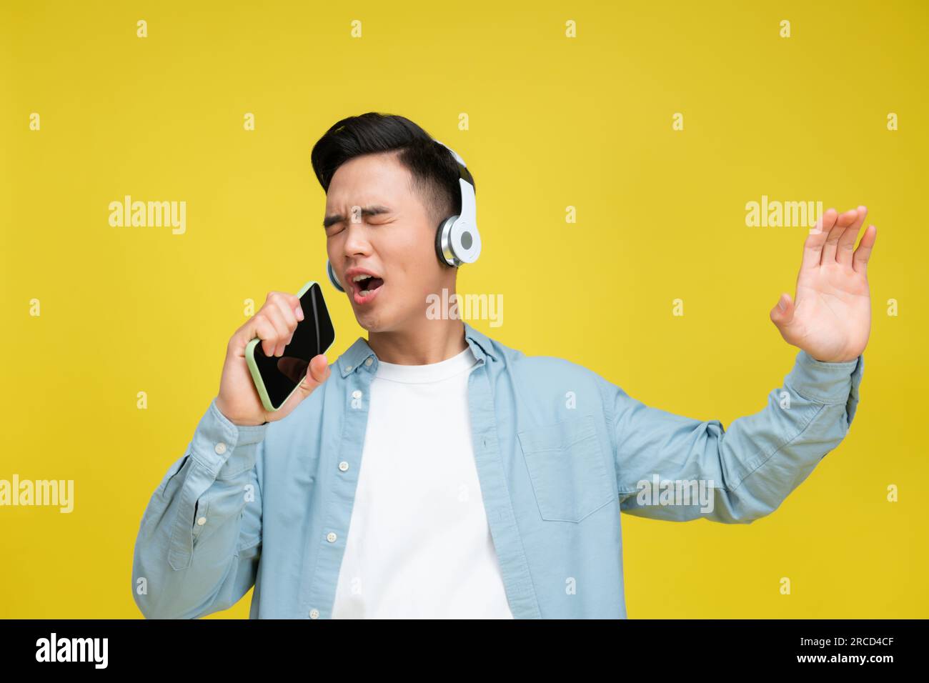 Jeune homme portant des écouteurs écouter de la musique chanter la chanson enregistrer la voix par téléphone portable dictaphone Banque D'Images