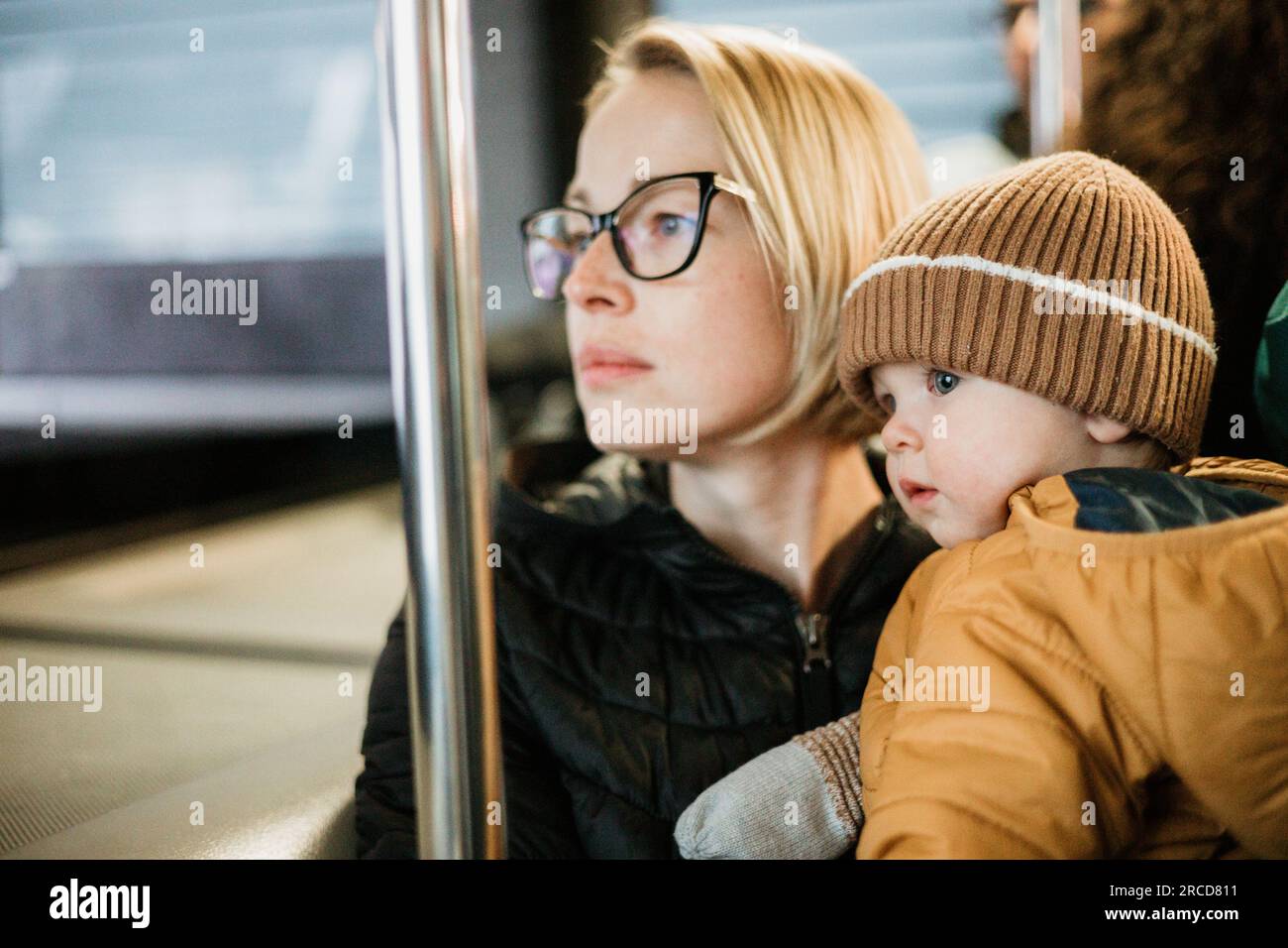 Mère porte son enfant tout en se tenant debout et en tenant sur le bus. Maman tenant son bébé garçon dans ses bras tout en conduisant dans un transport en commun. Adorable petit garçon voyageant avec sa mère Banque D'Images