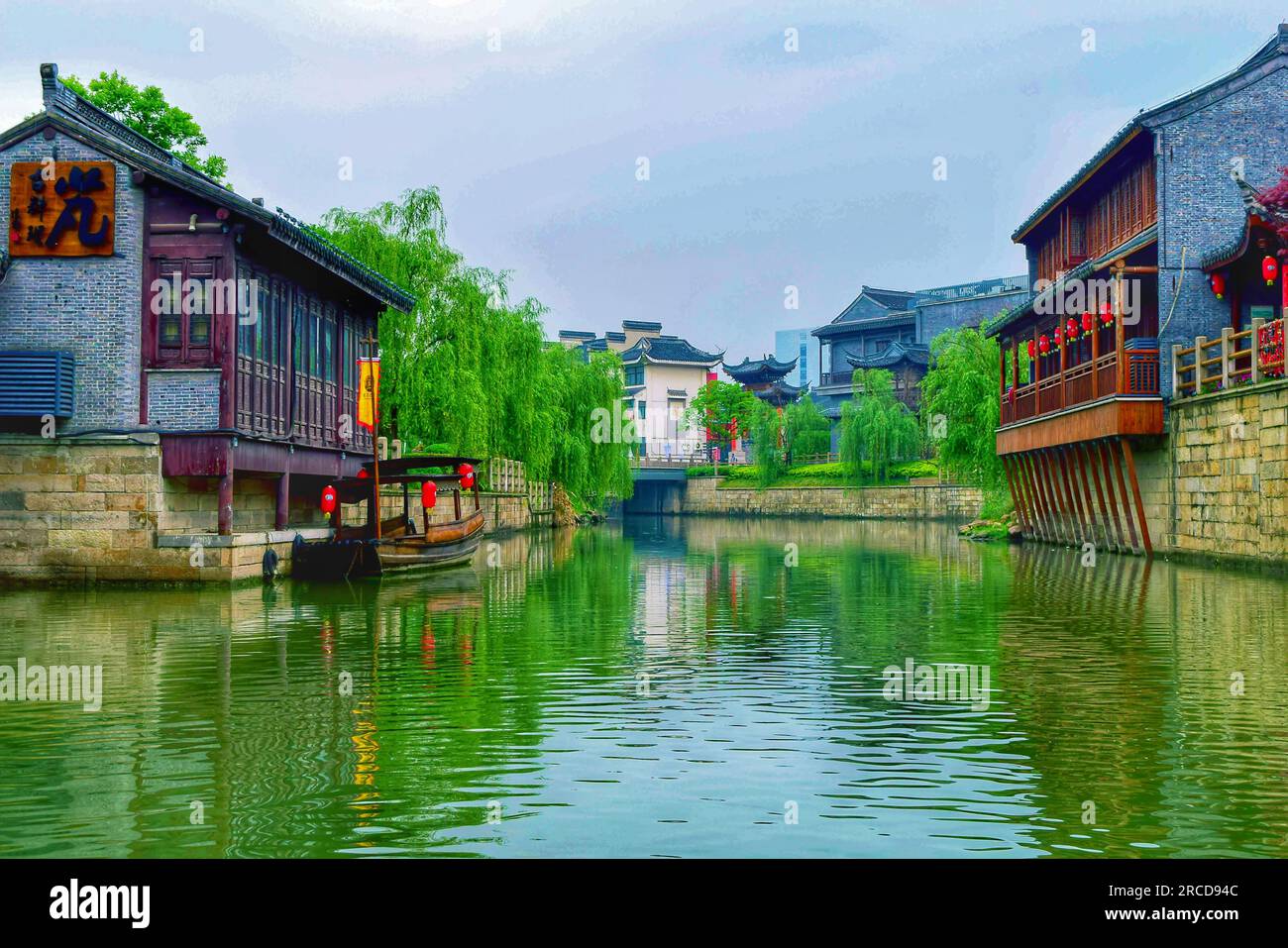 Découvrez le mélange harmonieux d'une belle rivière, d'arbres verdoyants et de maisons traditionnelles se prélassant dans l'étreinte douce de la lumière du soleil. Banque D'Images