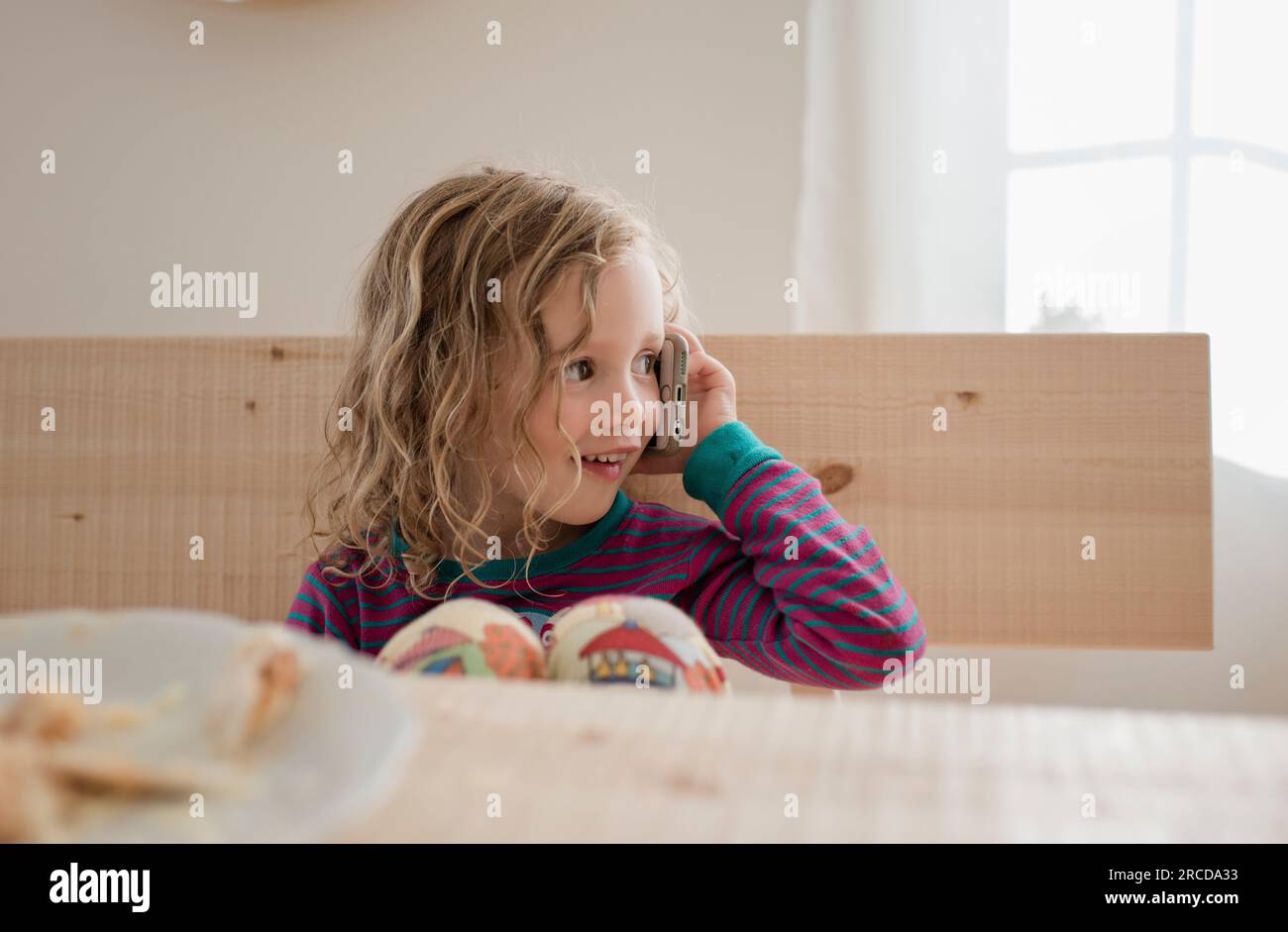 portrait d'une jeune fille assise à la maison en utilisant un téléphone portable Banque D'Images