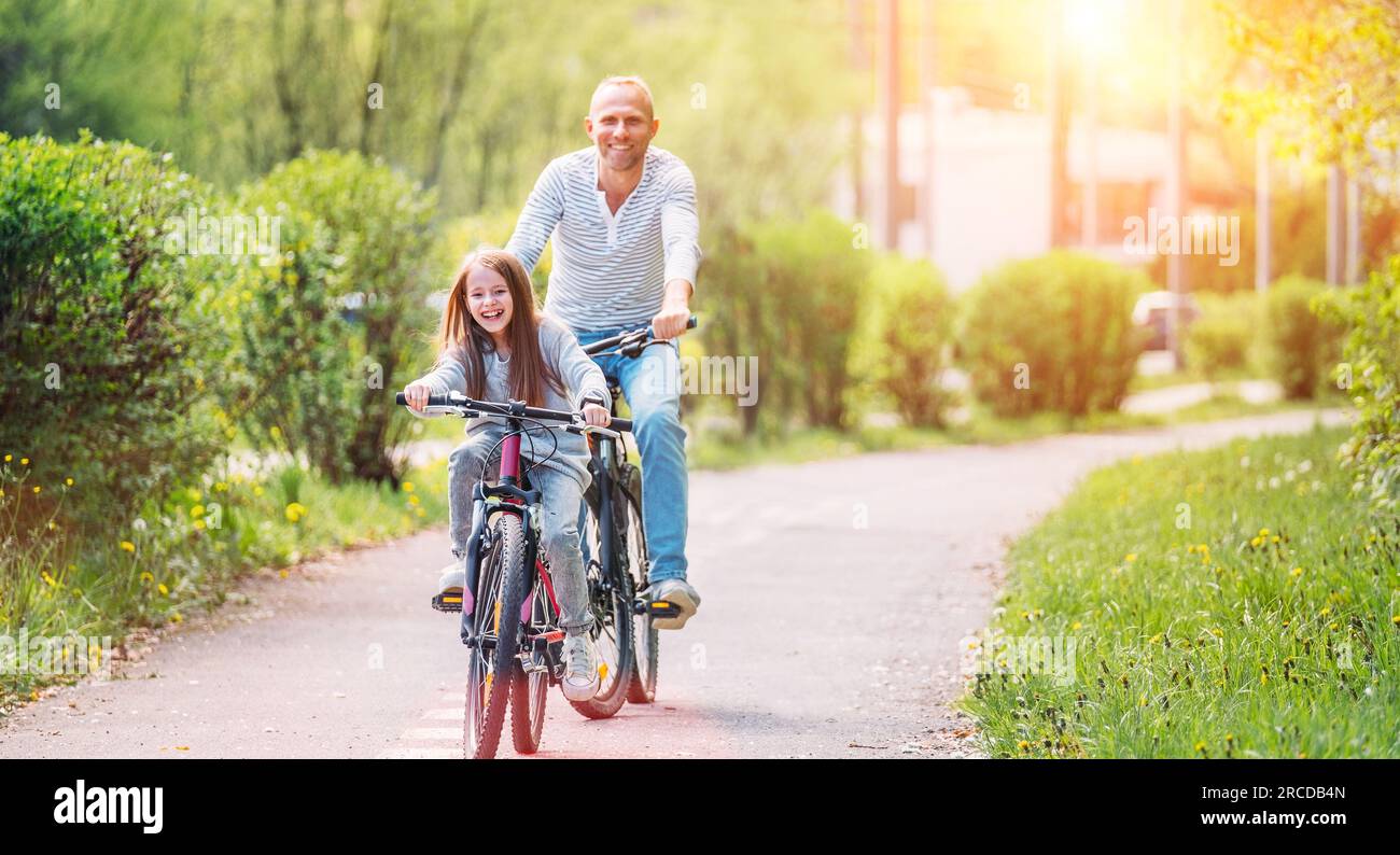 Portraits souriant père avec fille pendant l'été randonnée à vélo en plein air. Ils apprécient la convivialité dans le parc de la ville d'été. Bonne parentalité et chi Banque D'Images