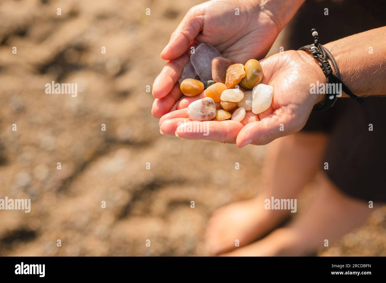 Les mains de la femme tenant des rochers et du verre de plage ramassés sur la plage Banque D'Images