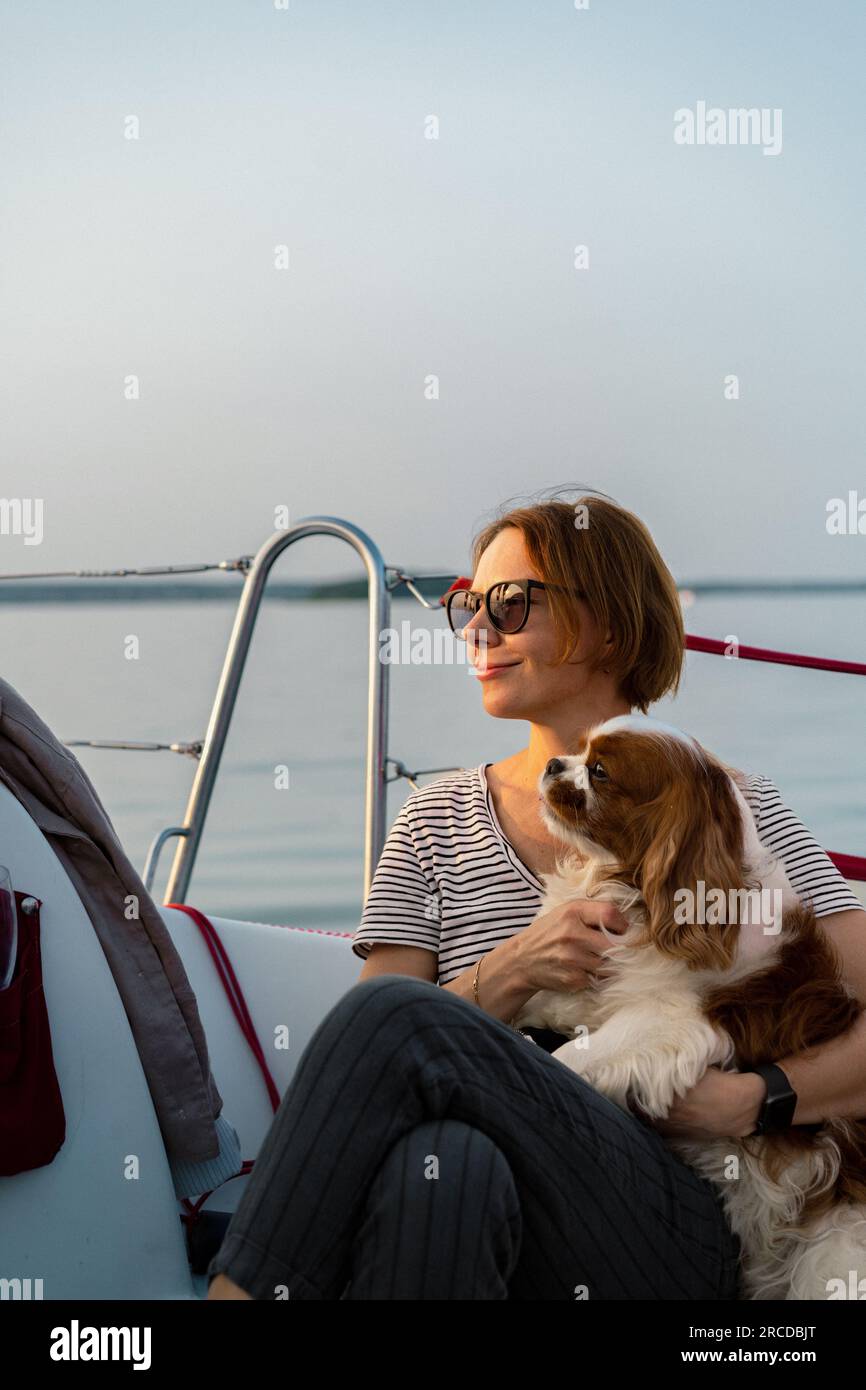 Jeune femme sur un yacht avec un chien, cavalier King Charles Spaniel Banque D'Images