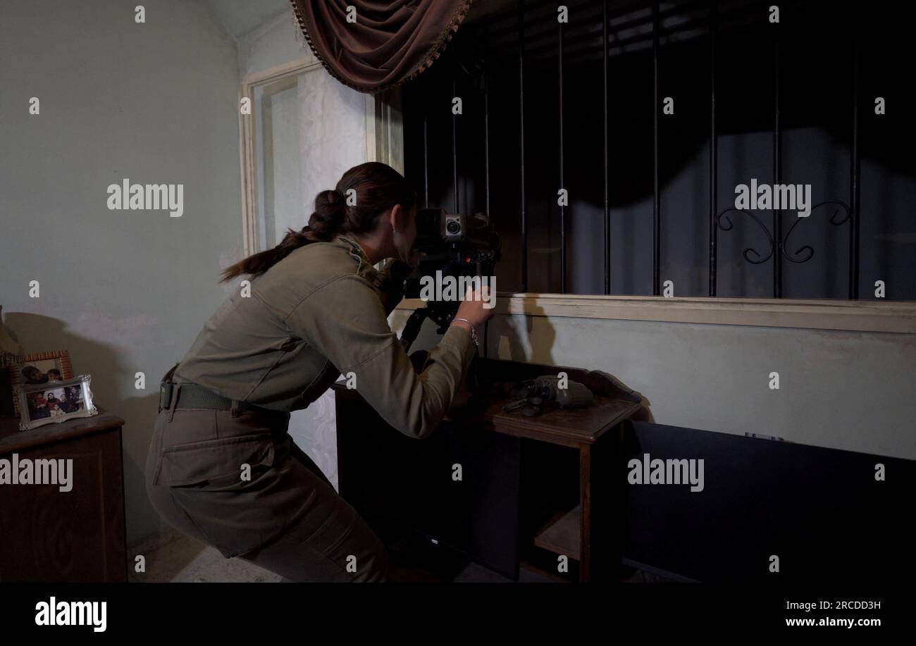 Une soldat israélienne regarde une vue virtuelle à l'aide de jumelles avancées à l'intérieur d'une pièce qui simule une résidence arabe au Centre d'entraînement à la guerre urbaine de Tze'elim de l'armée israélienne le 12 juillet 2023 dans le désert du Néguev, en Israël. Le Tse'elim Urban Warfare Training Center surnommé 'Baladia' (arabe pour 'district') est une maquette d'un village générique du moyen-Orient construit et financé en grande partie par l'aide militaire américaine, pour la formation des unités de combat, et se compose d'une imitation de la ville de style arabe. Banque D'Images