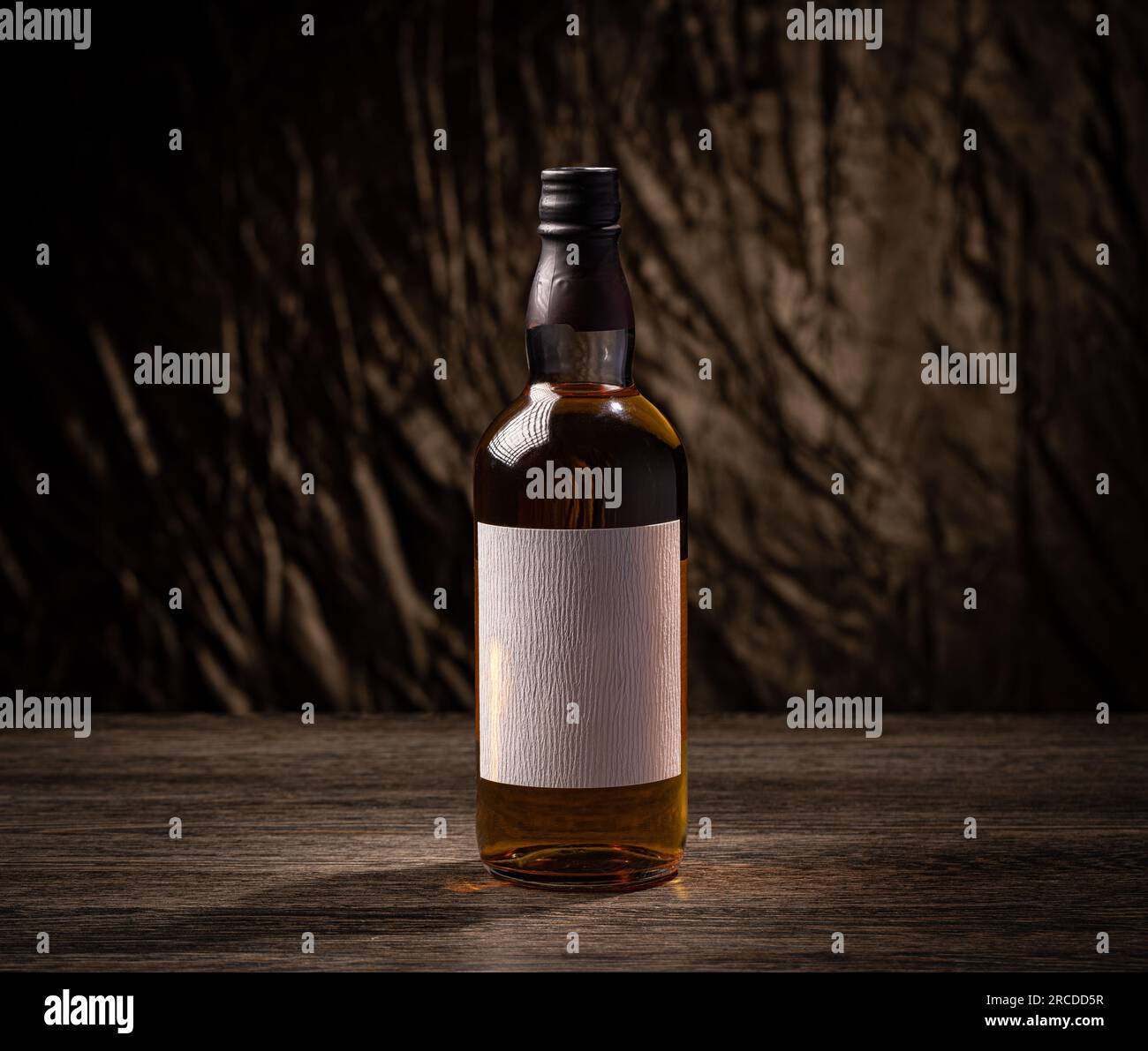 Bouteille de whisky avec étiquette vierge sur planche en bois Banque D'Images