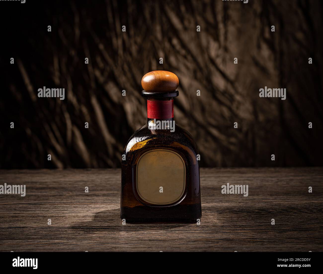 Bouteille pleine de whisky avec étiquette vierge sur planche en bois Banque D'Images