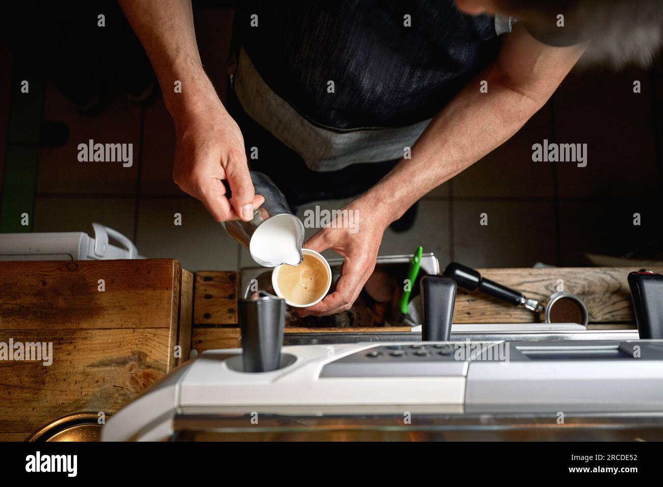 Détail de la vue de dessus de l'homme caucasien versant du lait dans une tasse de café Banque D'Images