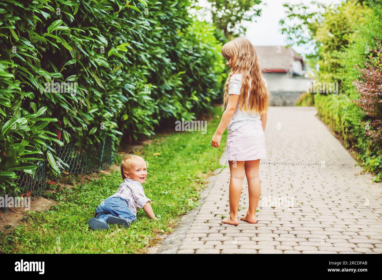 Deux enfants mignons jouant à l'extérieur, bébé garçon et petite fille s'amusant ensemble sur une belle journée d'été Banque D'Images