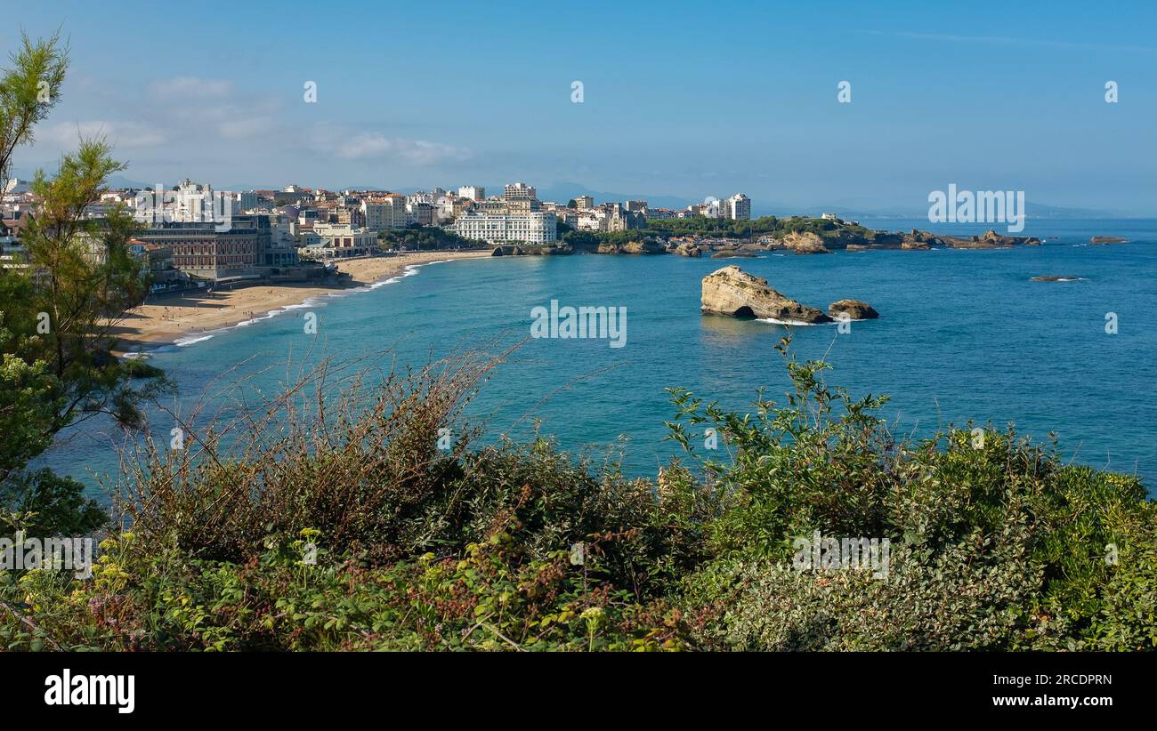 Biarritz, France, 2021. Panorama sur la plage de Miramar et les bâtiments en front de mer, et vue sur le rocher voûté dans la baie (Roche ronde aka Roche percée) Banque D'Images