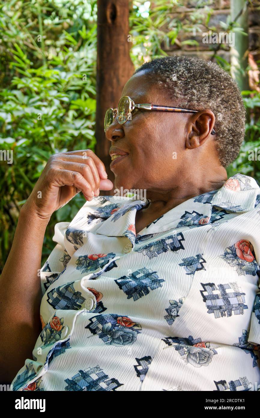 vieille femme africaine souriante assise dehors à une terrasse Banque D'Images