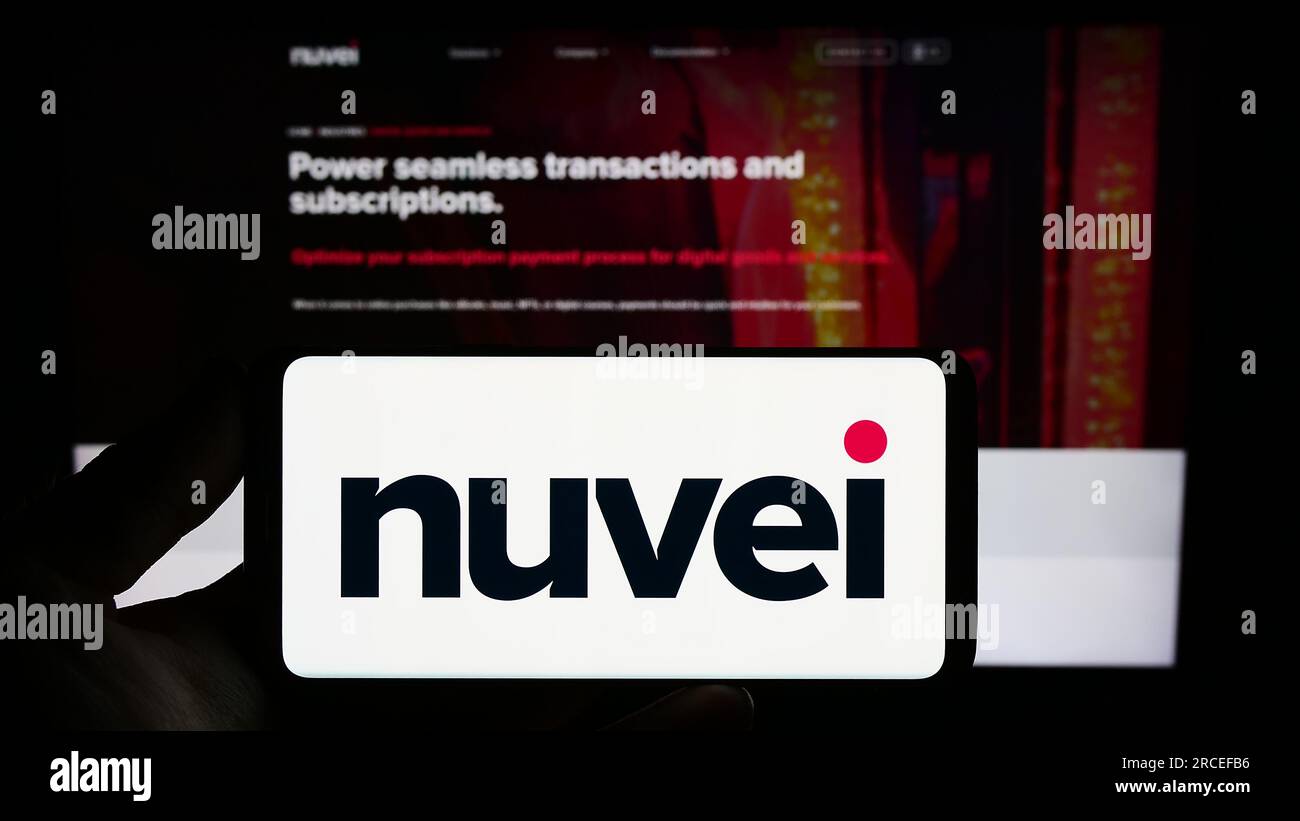 Personne tenant smartphone avec logo de la société de paiements Nuvei technologies Corp. sur l'écran en face du site Web. Concentrez-vous sur l'affichage du téléphone. Banque D'Images