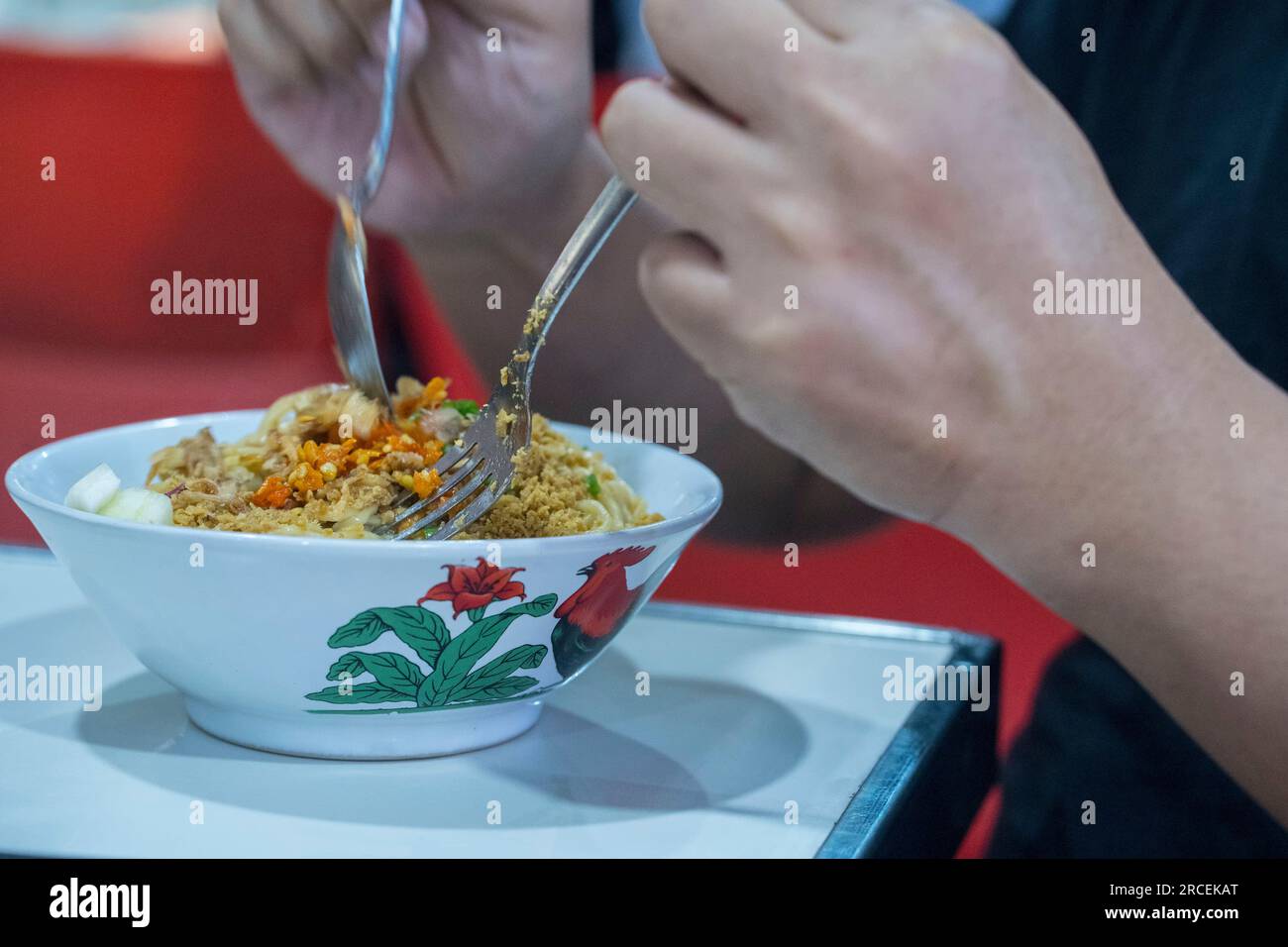 Gros plan de deux mains Préparez-vous à manger Mie Ayam ou un plat indonésien populaire composé de nouilles de poulet savoureuses et savoureuses. Photographie culinaire. Banque D'Images