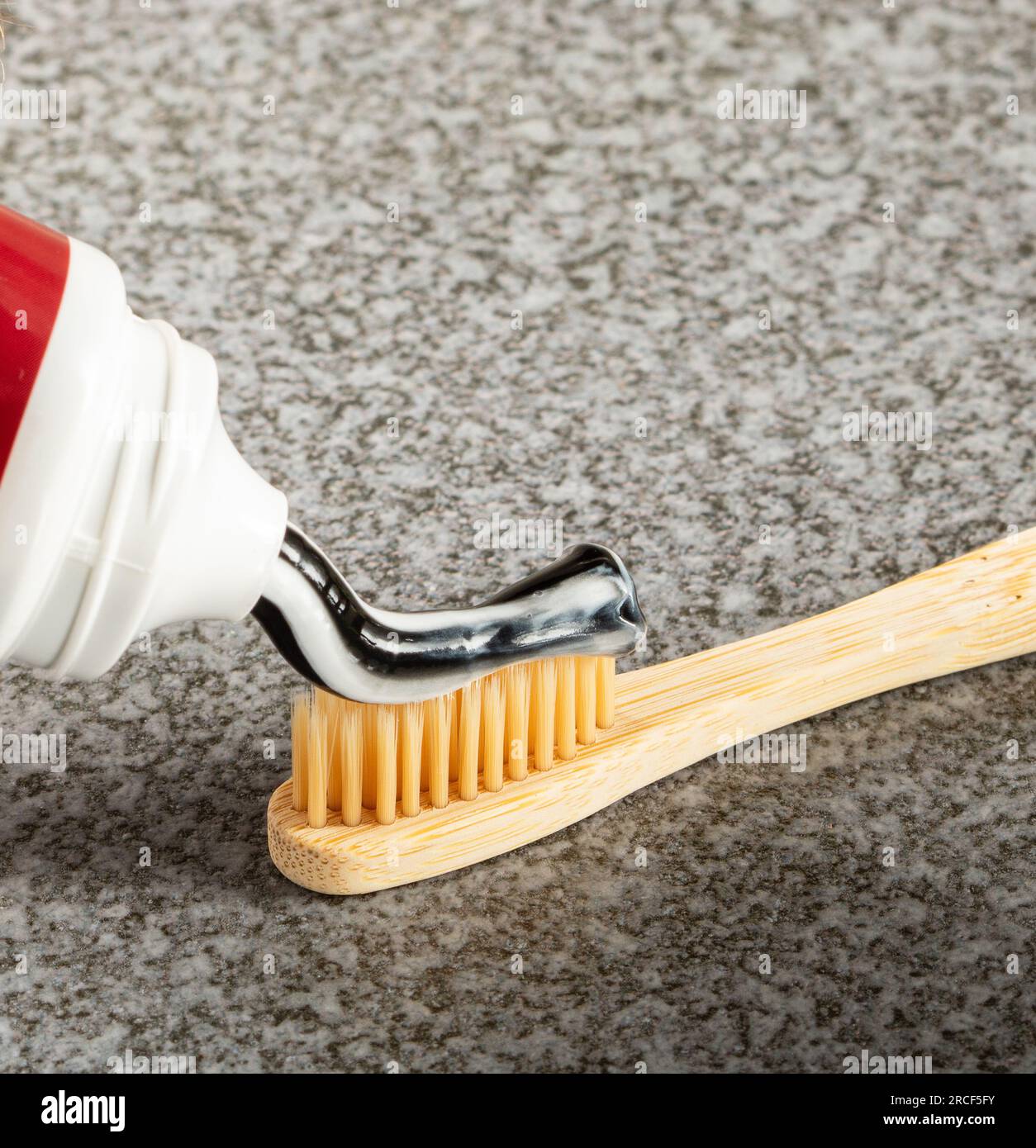 Dentifrice écologique au charbon actif appliqué sur une brosse à dents en bambou. Banque D'Images