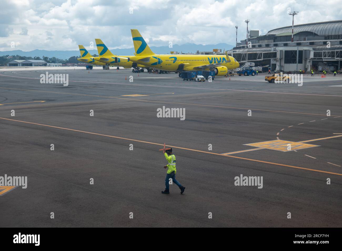 Medellin, Antioquia, Colombie - 23 octobre 2022 : le contrôleur de la circulation aérienne avec un gilet jaune fluorescent descend la piste de l'aéroport avec des Cros Orange Cones Banque D'Images