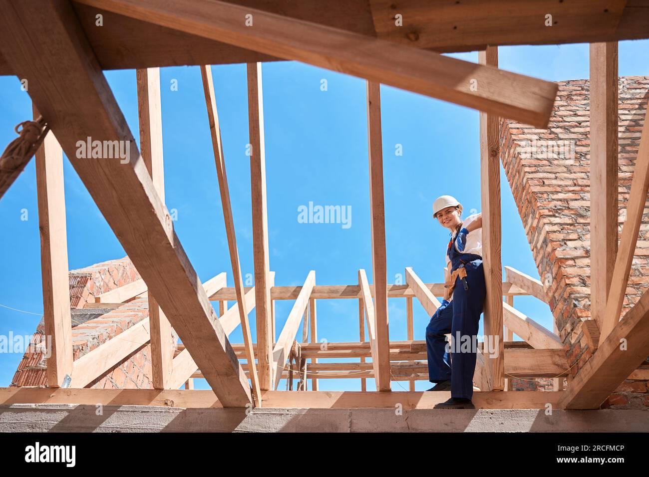 Femme ingénieur du bâtiment debout sur la poutre en bois du cadre de toit Banque D'Images