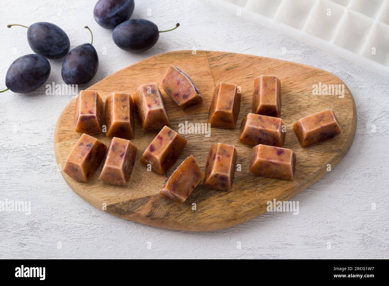Purée de prunes congelée et prune fraîche sur un fond gris clair. Banque D'Images