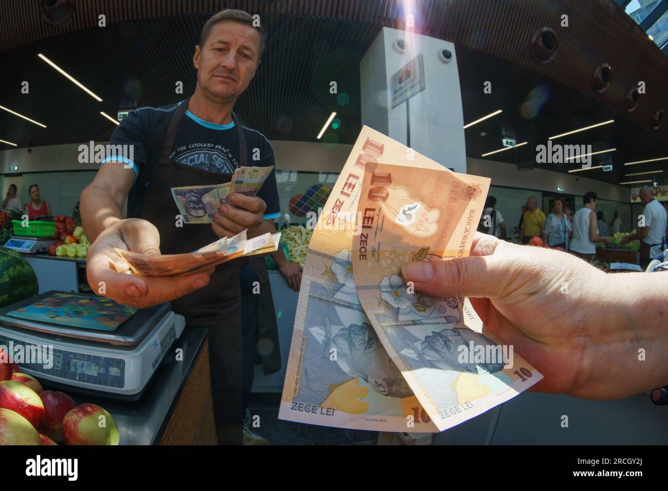 Bucarest, Roumanie. 14 juillet 2023 : un agriculteur roumain reçoit des billets de banque roumains en leu d'un client lors de l'inauguration du marché agroalimentaire 'Piata Norilor' par la mairie du secteur 4, Bucarest. Piața Norilor, le plus récent et l'un des plus modernes de la capitale, a été reconstruit sur son ancien site après la démolition de l'ancien marché d'un étage et a maintenant deux étages, Au rez-de-chaussée se trouve un parking et au premier étage se trouve le marché agroalimentaire adressé aux agriculteurs roumains. Crédit : Lucian Alecu/Alamy Live News Banque D'Images