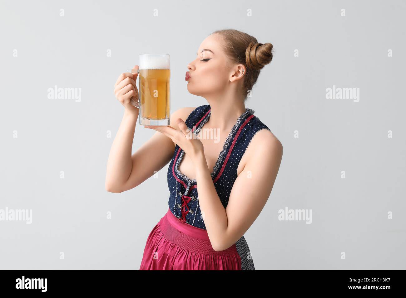 Magnifique serveuse d'octobre avec baiser soufflant de la bière sur fond clair Banque D'Images