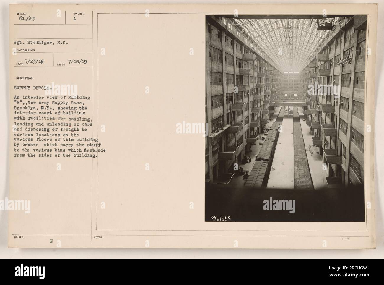 Vue de l'intérieur du bâtiment B de la base d'approvisionnement de la Nouvelle armée à Brooklyn, New York La photographie capture la cour intérieure du bâtiment, montrant les installations pour la manutention, le chargement et le déchargement des voitures et l'élimination du fret à divers endroits. Les grues sont visibles, transportant des matériaux vers des bacs sur les côtés du bâtiment. Photographie prise le 18 juillet 1919 par le sergent Steiniger. Banque D'Images