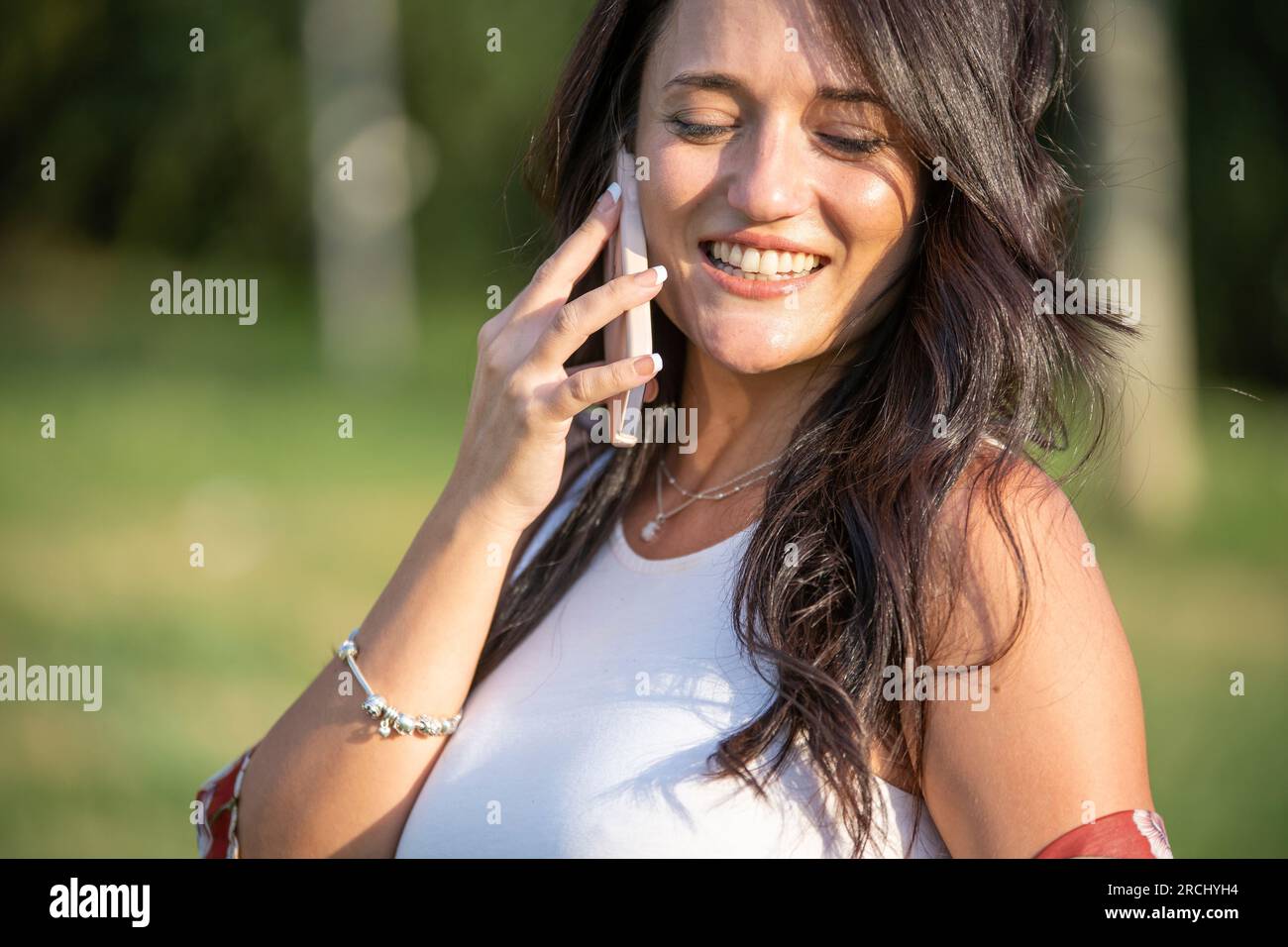 Plan rapproché d'une femme riant en parlant au téléphone à l'extérieur dans un parc. Concept technologique. Banque D'Images