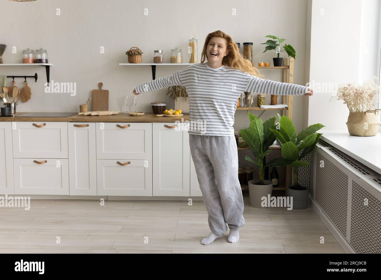Femme heureuse dans les vêtements décontractés à la maison dansant dans la cuisine Banque D'Images