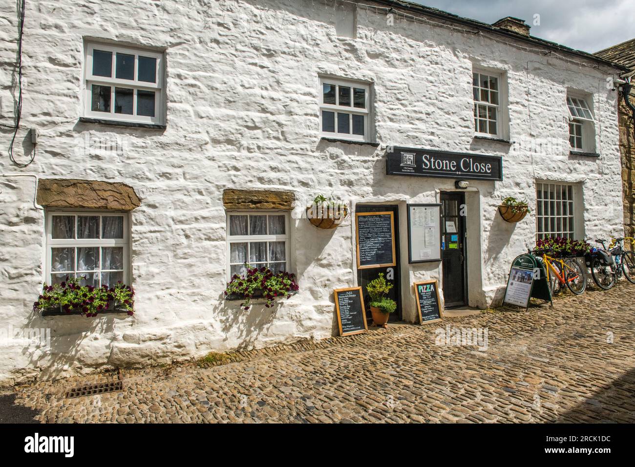 Stone Close - une excellente pizzeria que vous entrez dans Dent - avec ses murs blanchis à la chaux et les pavés dans la route, à Dentdale - une partie de Cumbria Banque D'Images