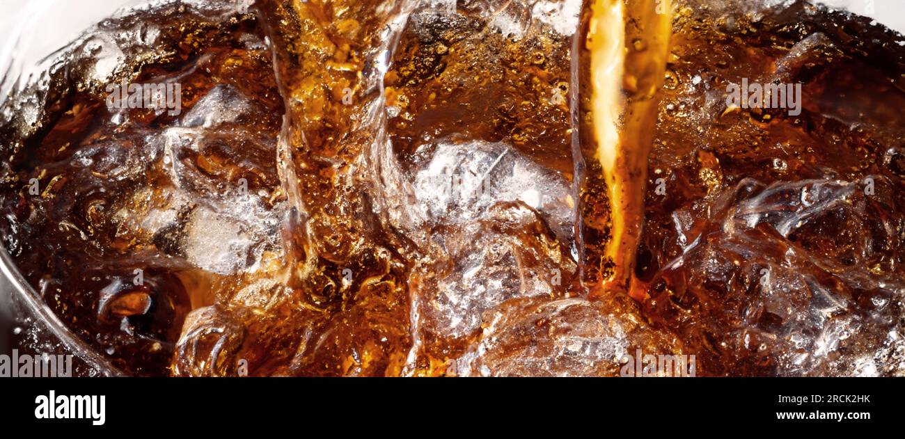 Éclaboussures de Cola et de glace. Soda de Cola et de glace éclaboussant ou flottant jusqu'au sommet de la surface. Gros plan de glace dans de l'eau de cola. Texture du carbonate d Banque D'Images