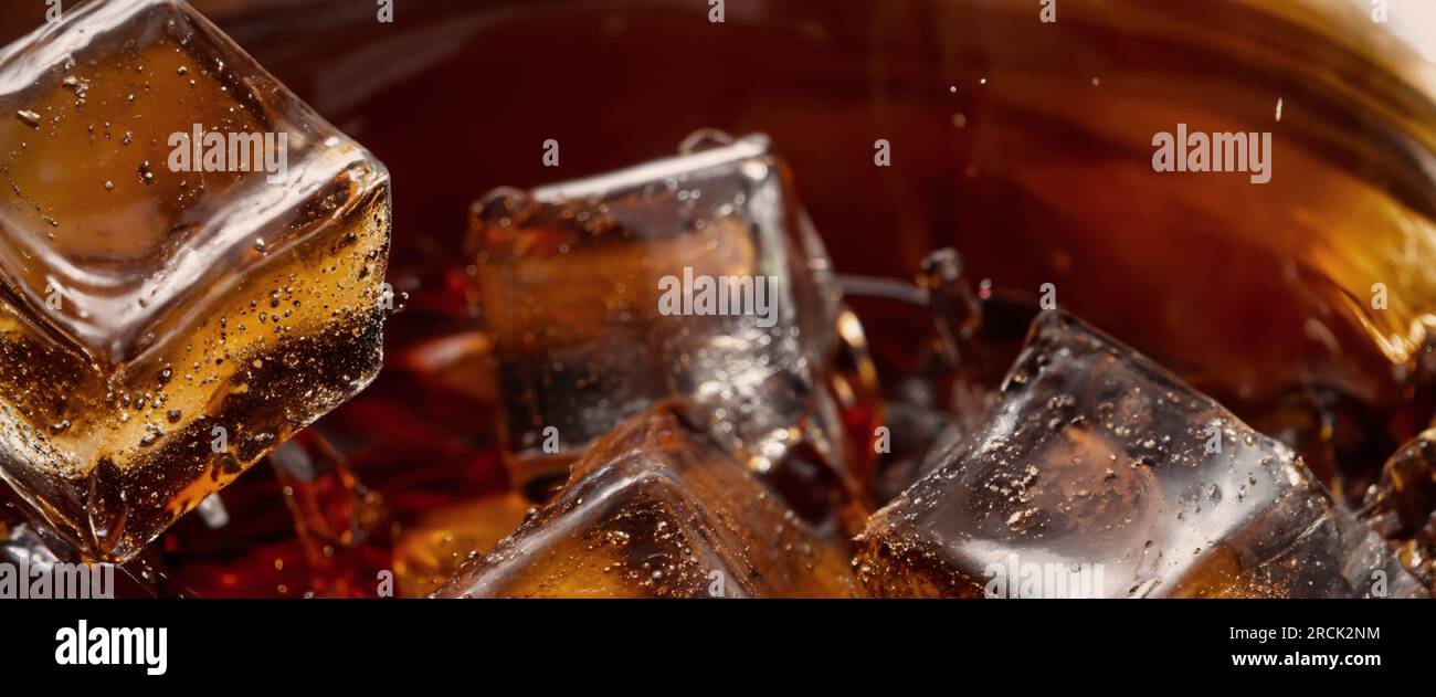 Éclaboussures de Cola et de glace. Soda de Cola et de glace éclaboussant ou flottant jusqu'au sommet de la surface. Gros plan de glace dans de l'eau de cola. Texture du carbonate d Banque D'Images