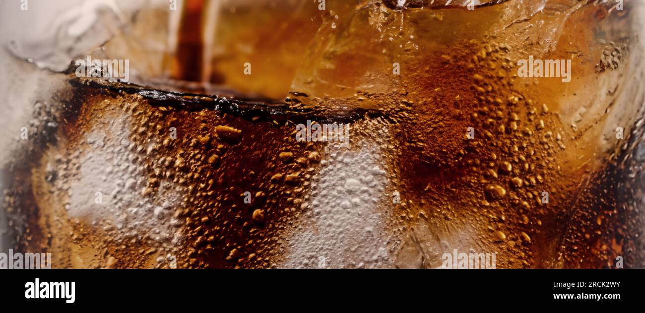 Éclaboussures de Cola et de glace. Soda de Cola et de glace éclaboussant ou flottant jusqu'au sommet de la surface. Gros plan de glace dans de l'eau de cola. Texture du carbonate d Banque D'Images