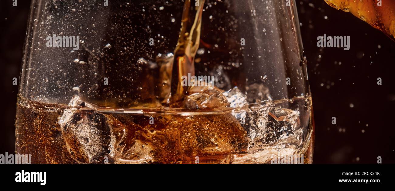 Éclaboussures de Cola et de glace. Soda de Cola et de glace éclaboussant ou flottant jusqu'au sommet de la surface. Gros plan de glace dans de l'eau de cola. Texture du carbonate d Banque D'Images