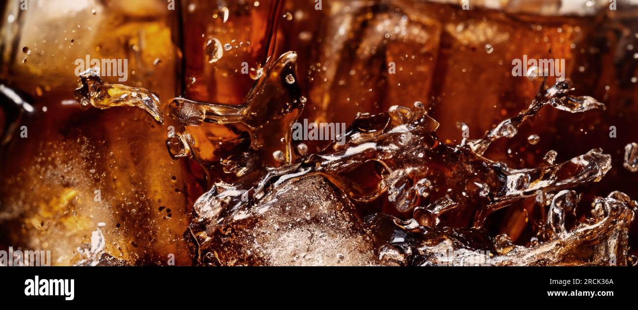 Éclaboussures de Cola et de glace. Soda de Cola et de glace éclaboussant ou flottant jusqu'au sommet de la surface. Gros plan de glace dans de l'eau de cola. Texture du carbonate d Banque D'Images