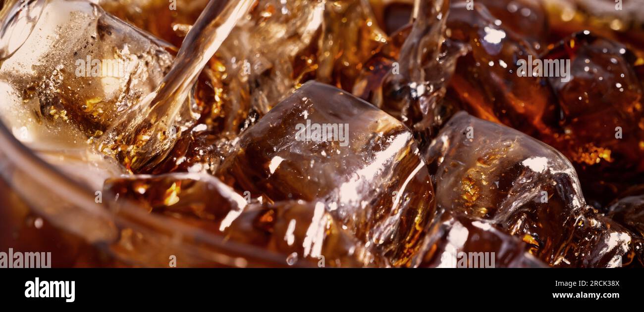 Éclaboussures de Cola et de glace. Soda de Cola et de glace éclaboussant ou flottant jusqu'au sommet de la surface. Gros plan de glace dans de l'eau de cola. Texture du carbonate d Banque D'Images
