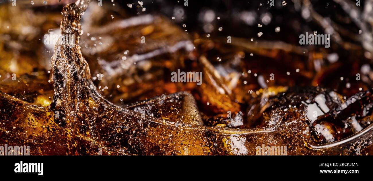 Éclaboussures de Cola et de glace. Soda de Cola et de glace éclaboussant ou flottant jusqu'au sommet de la surface. Gros plan de glace dans de l'eau de cola. Texture du carbonate d Banque D'Images