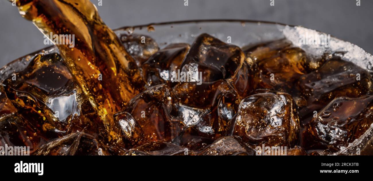 Éclaboussures de Cola et de glace. Soda de Cola et de glace éclaboussant ou flottant jusqu'au sommet de la surface. Gros plan de glace dans de l'eau de cola. Texture du carbonate d Banque D'Images