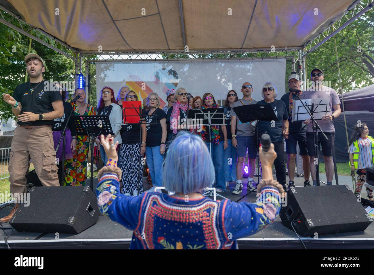 Southend on Sea, Royaume-Uni. 15 juillet 2023. Un groupe d'interprètes chantent et parlent sur une scène en plein air lors de Southend Pride à Southend-on-Sea, Essex. L'ensemble comprend une quinzaine d'individus avec pupitres à musique et microphones, dirigés par un chef d'orchestre coloré face au groupe. L’événement célèbre la fierté LGBTQ+, l’inclusion et l’expression artistique locale. Des milliers de personnes participent à la parade annuelle de la fierté sur la rue principale et au festival sur la place des guerriers. Penelope Barritt/Alamy Live News Banque D'Images