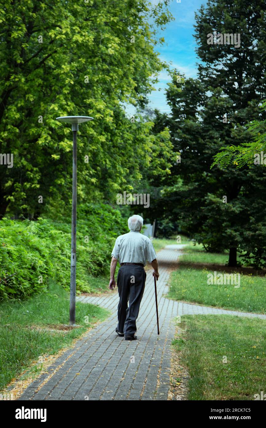 Un vieil homme se repose assis sur le banc dans le parc Banque D'Images