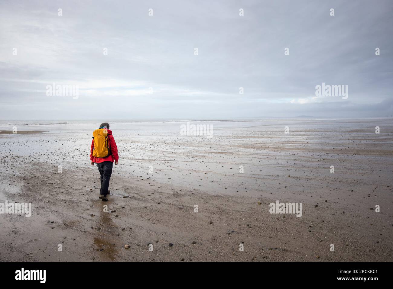 Walker sur une plage vide, Kenfig Beach, pays de Galles, Royaume-Uni Banque D'Images