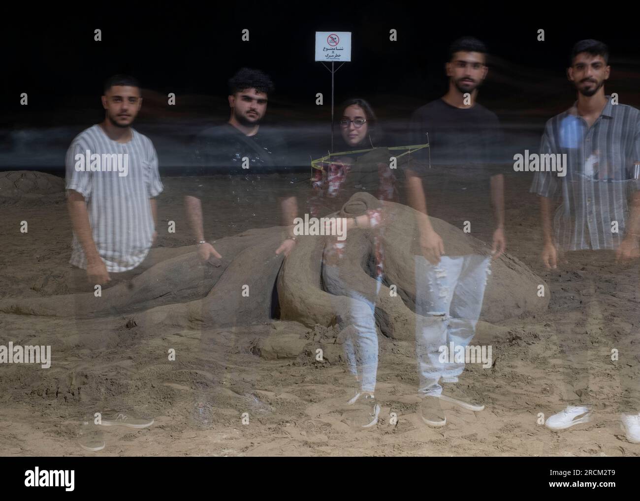 Des jeunes en Iran posent pour une photographie devant une sculpture de sable au Festival national de sculpture de sable de Babolsar sur la côte sud de la mer Caspienne dans la province de Mazandaran, à 235 km (146 miles) au nord de Téhéran, le 13 juillet 2023. La ville de Babolsar accueille le festival, qui met en valeur la créativité et le talent des artistes locaux. Les visiteurs ont la chance de voir des sculptures de sable complexes créées par des artistes qualifiés utilisant uniquement du sable et de l'eau, célébrant le riche patrimoine culturel et la diversité artistique de l'Iran. (Photo de Morteza Nikoubazl/NurPhoto) Banque D'Images