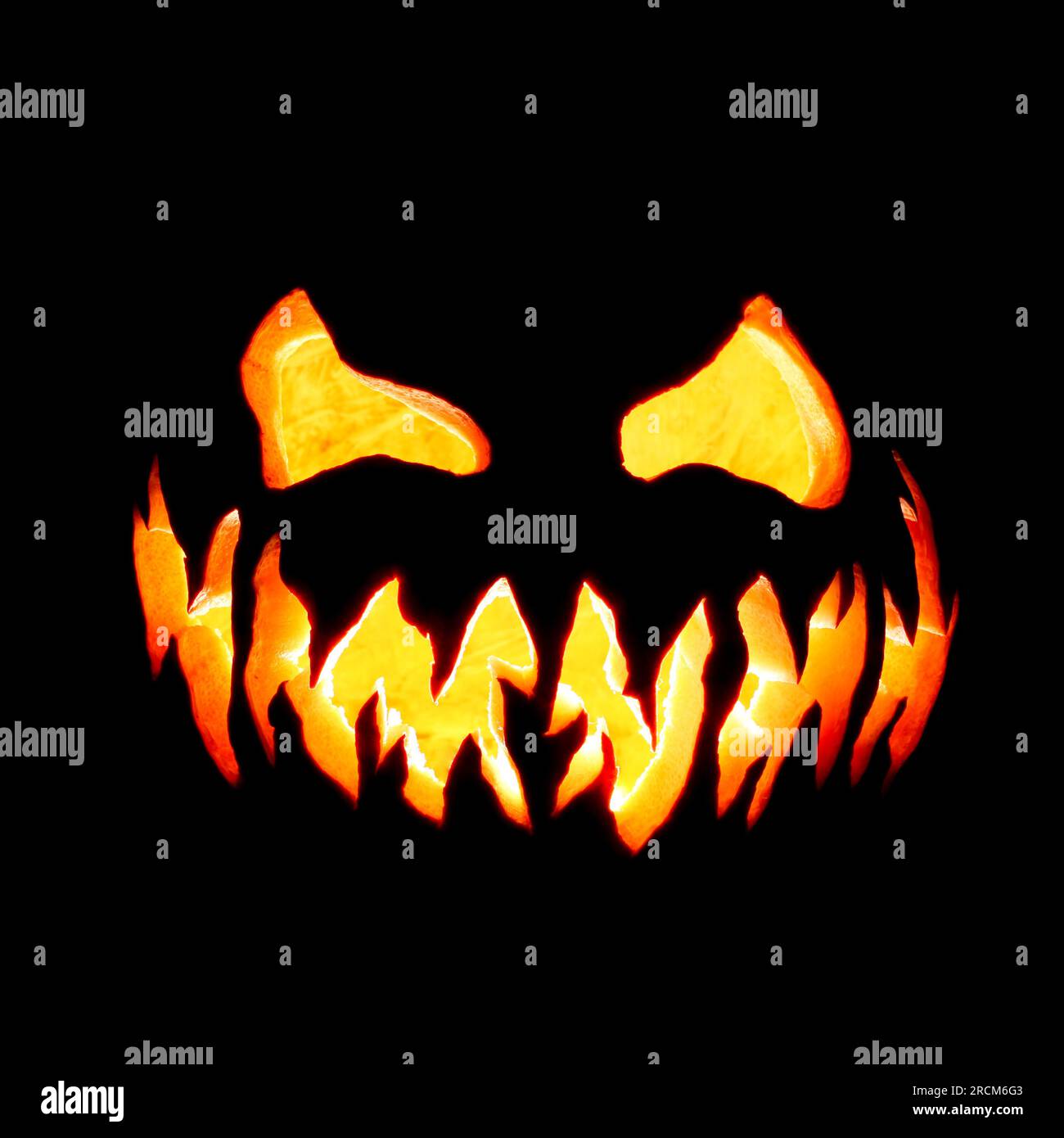 Scary Halloween citrouille Jack o lanterne visage brillant rouge et jaune eerily sur noir Banque D'Images