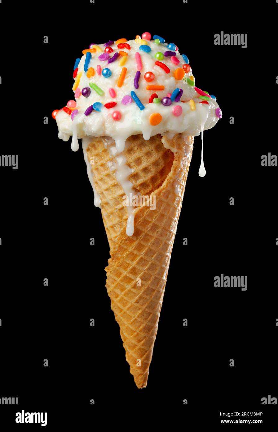 Gros plan de cône de crème glacée goutte à goutte et fondant avec de la glace à la vanille et un cône de gaufre recouvert de saupoudrages colorés isolés sur le noir Banque D'Images