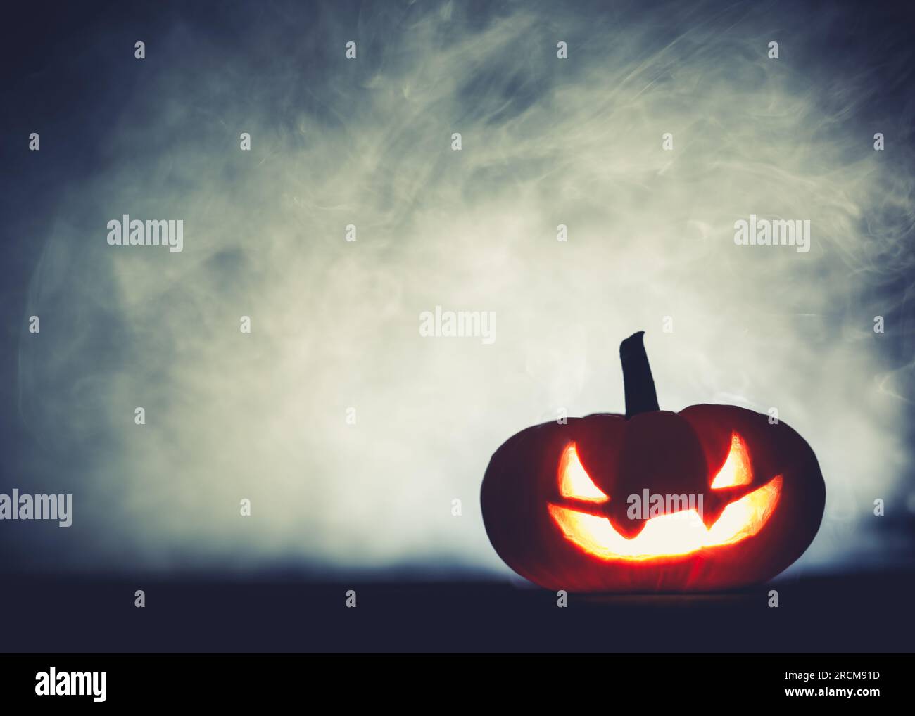 Spooky Halloween Jack o lanterne citrouille avec le visage grinning effrayant sculpté brillant dans la fumée la nuit d'Halloween. Banque D'Images