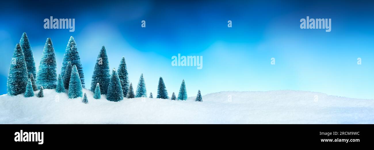 Figurines d'arbre de Noël forêt dans la neige étincelante avec ciel bleu vif. Banque D'Images