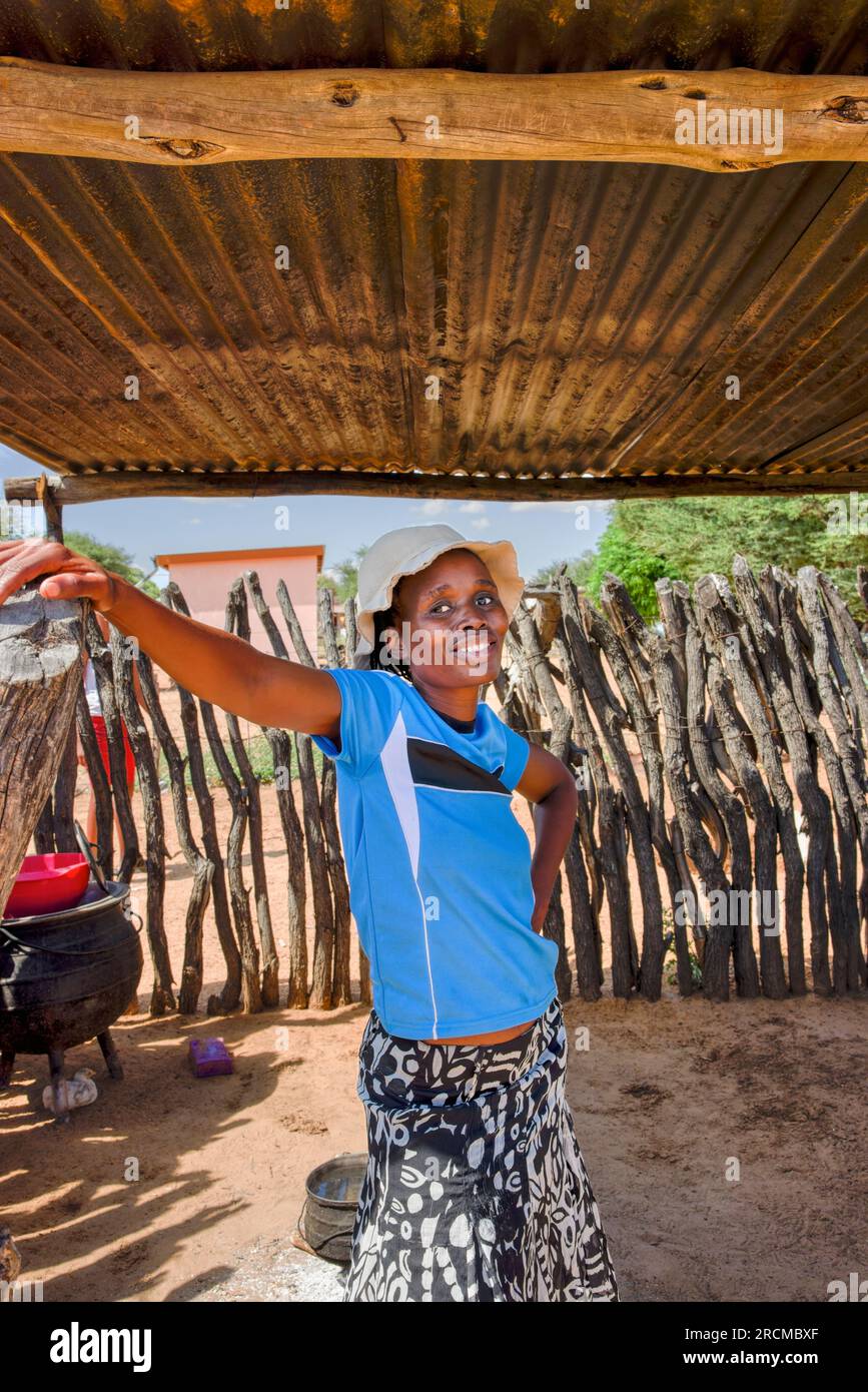 jeune femme africaine de village avec un chapeau debout sous le hangar d'une cabane de cuisine en plein air pour se rafraîchir Banque D'Images