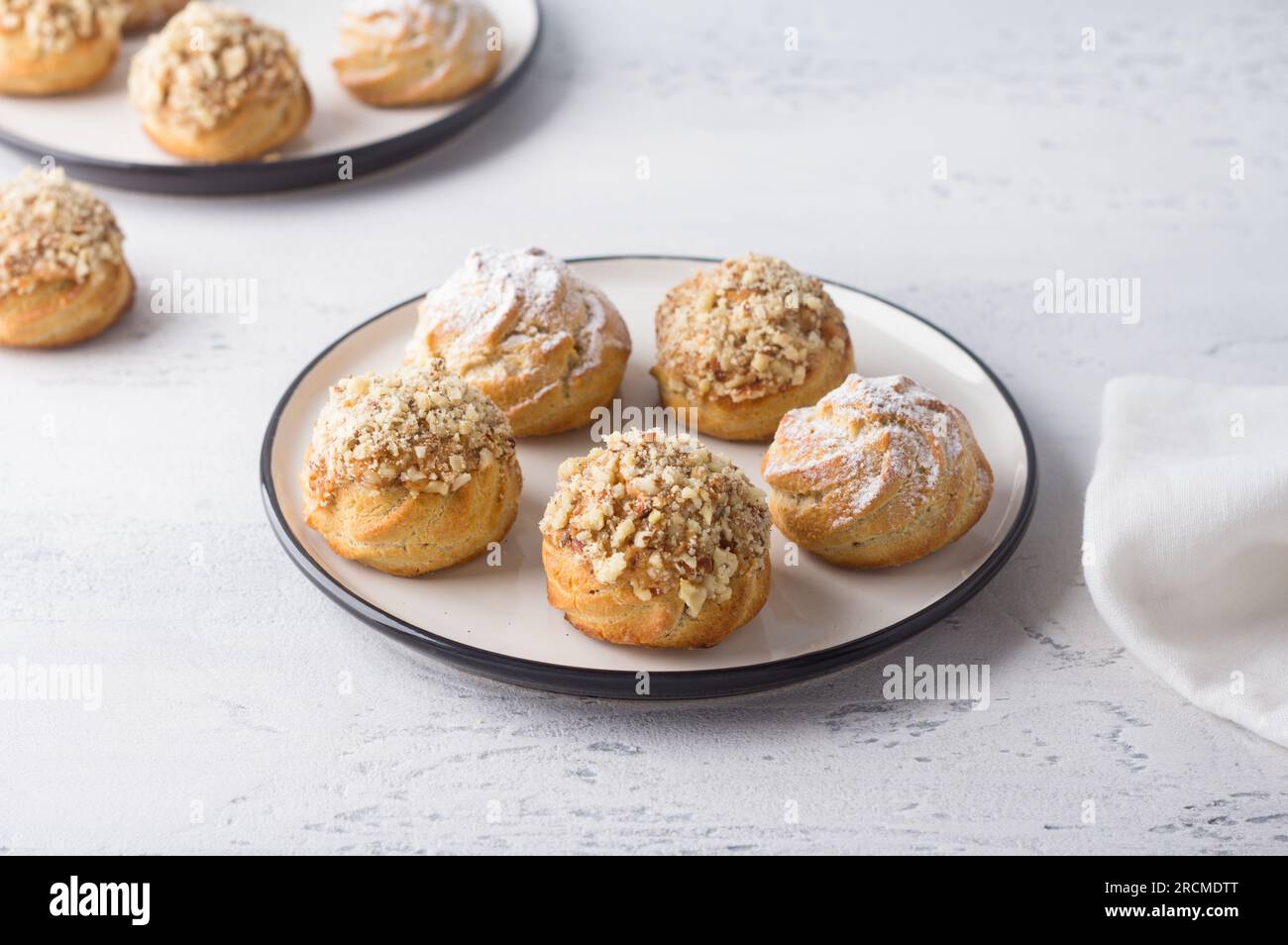 Profiteroles d'avoine sans gluten avec crème caramel de lait concentré bouilli, saupoudré de sucre en poudre et de noix sur un fond bleu clair, vue de dessus. Banque D'Images