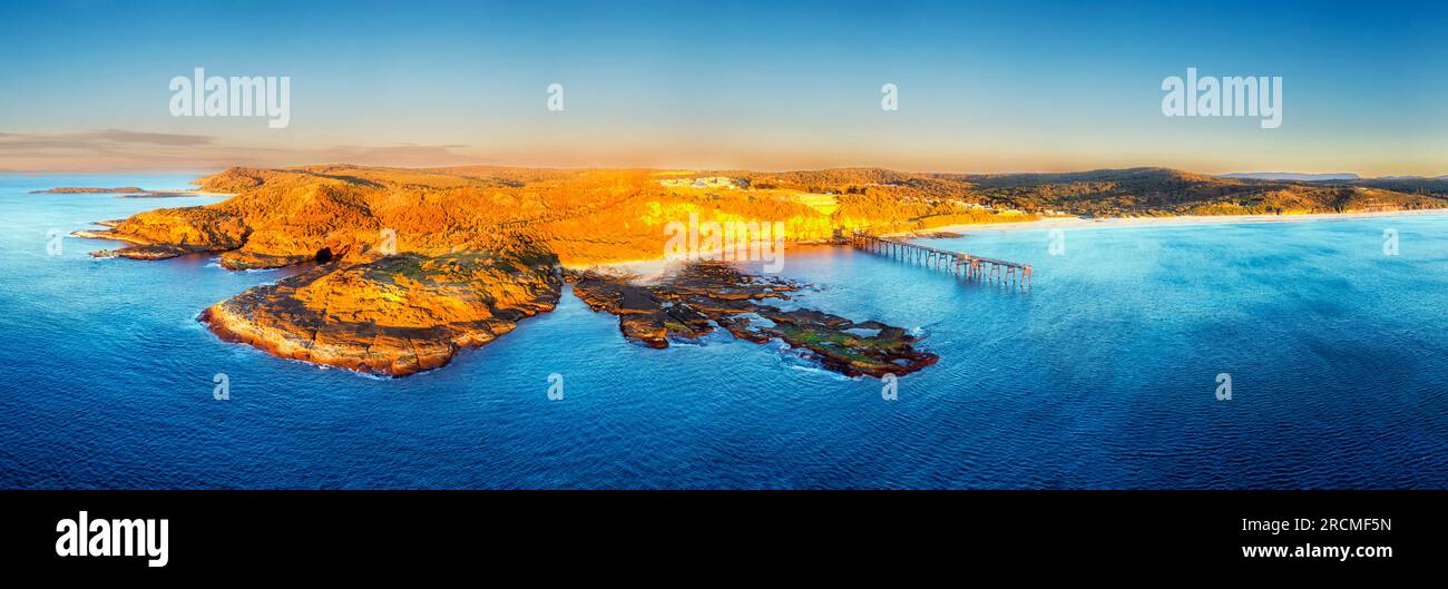 Plage de camp moyen sur la côte Pacifique de l'Australie à Catherine Hill Bay avec jetée historique - proche panorama aérien du lever du soleil. Banque D'Images